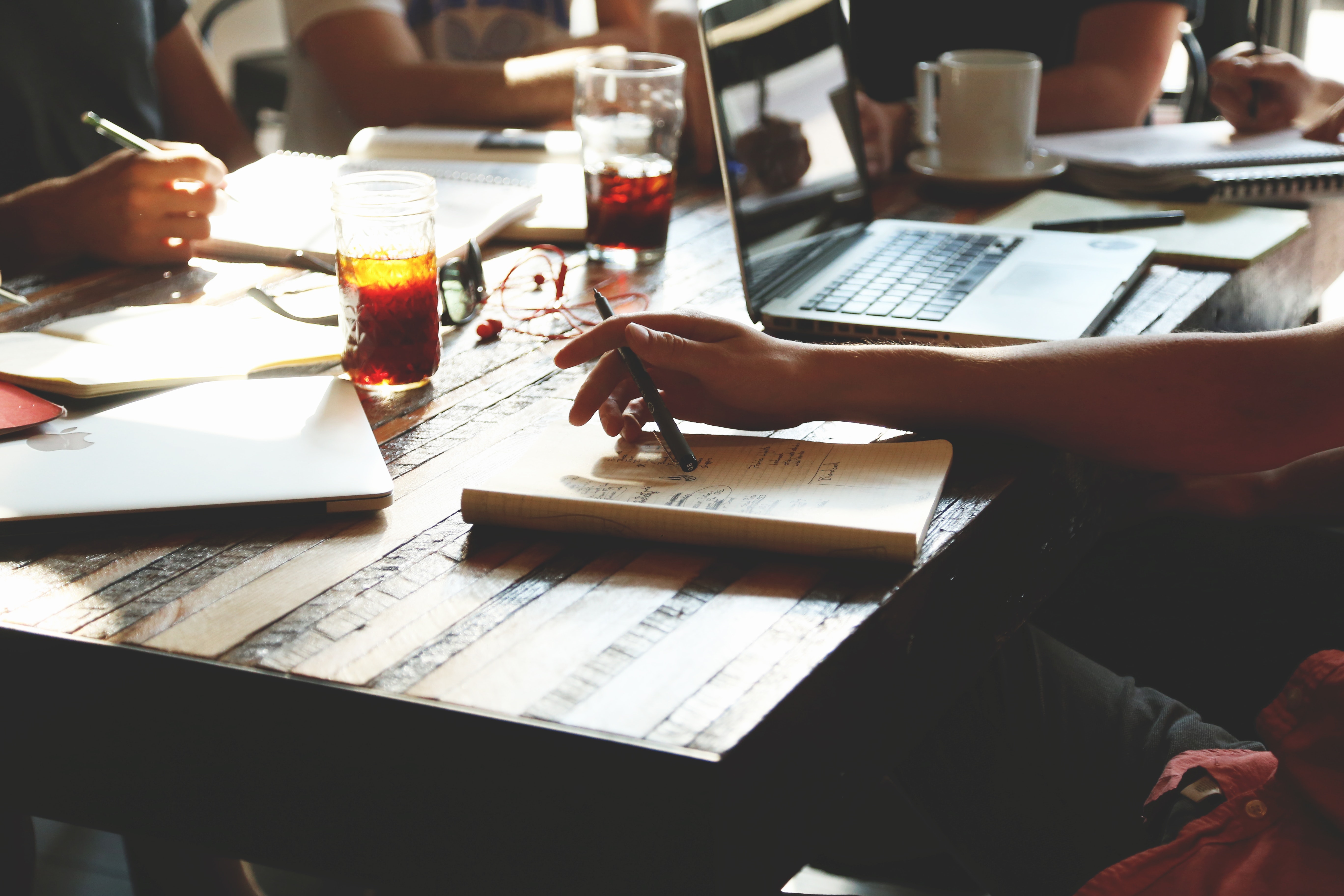 Hands and laptop on cluttered desk during meeting about performance management system