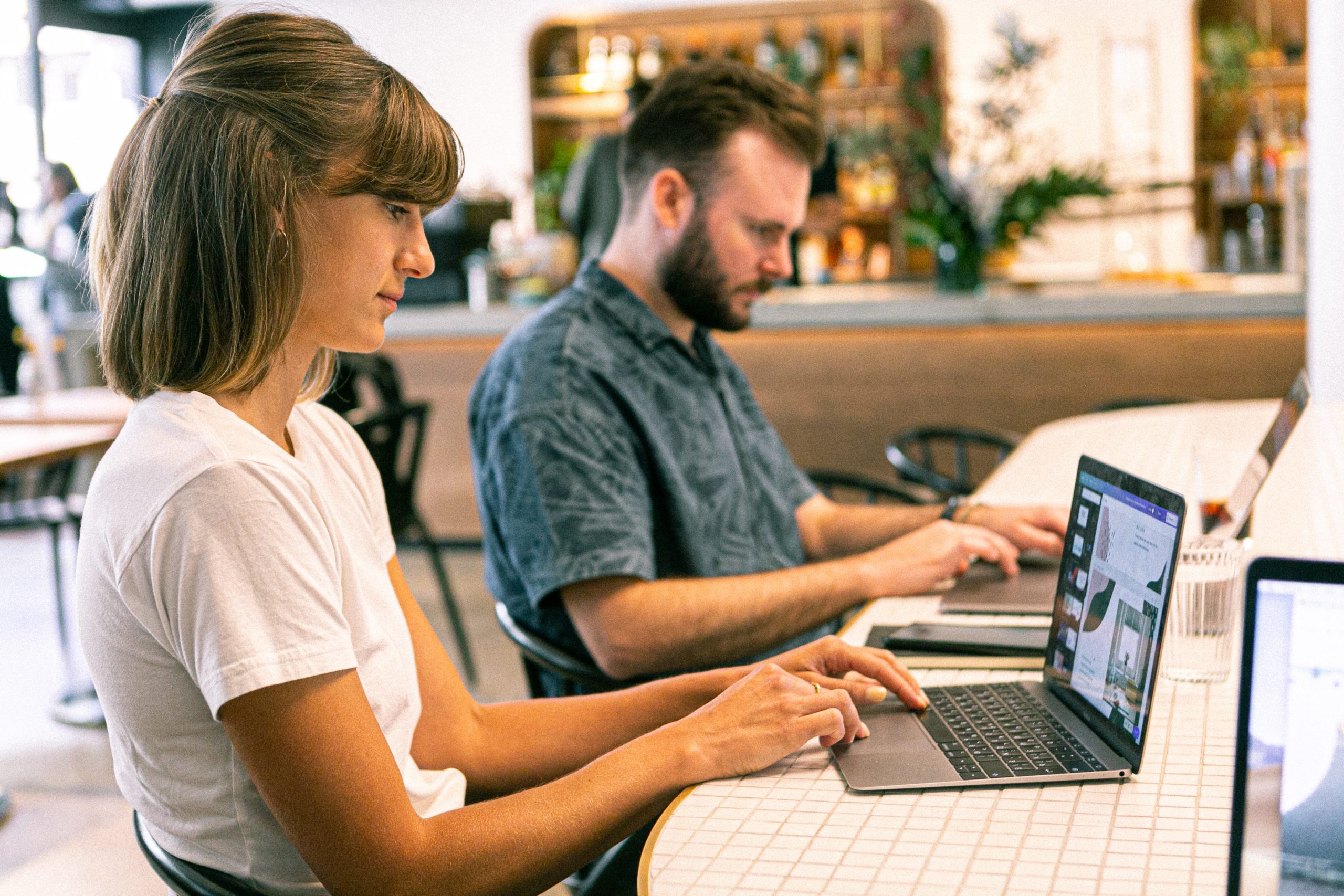 Woman and man using laptops in coffee shop