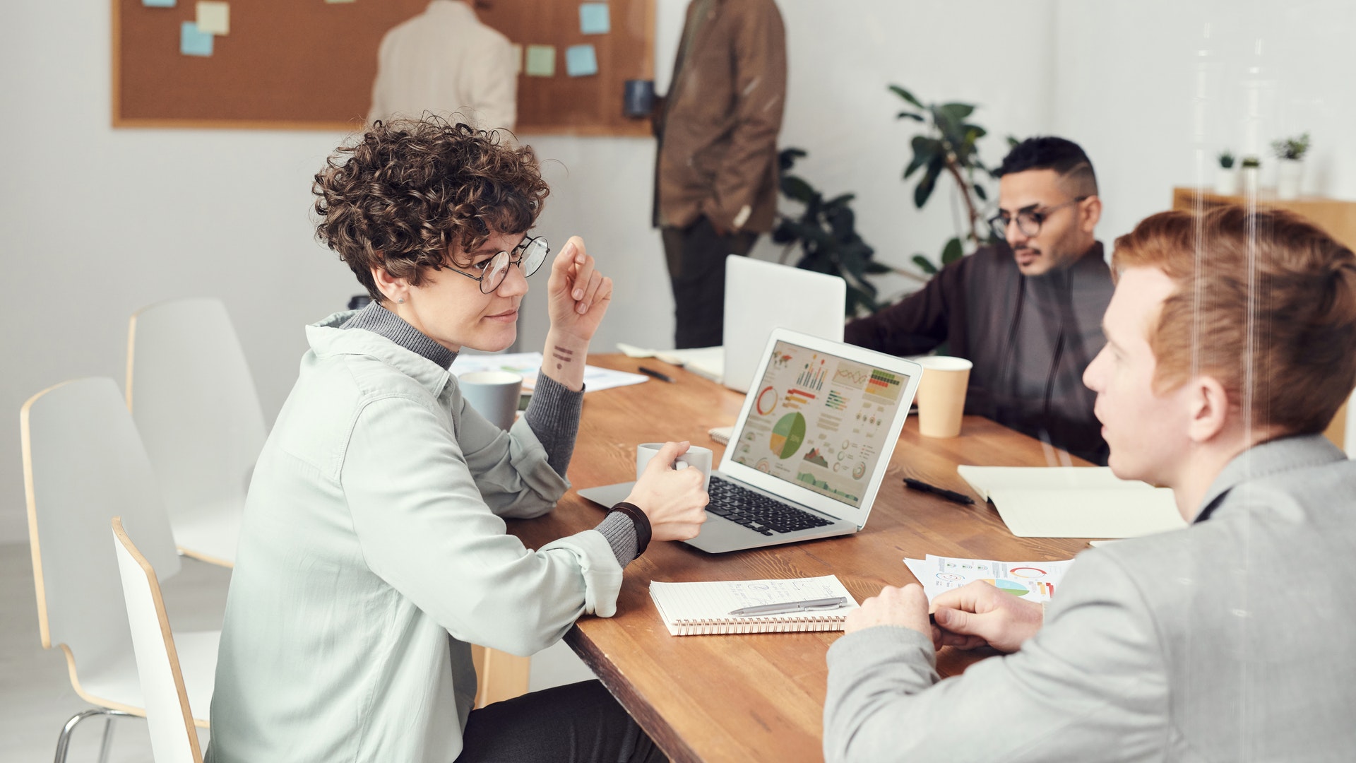 woman-desk-colleagues-office Woman sitting at desk in meeting with direct reports