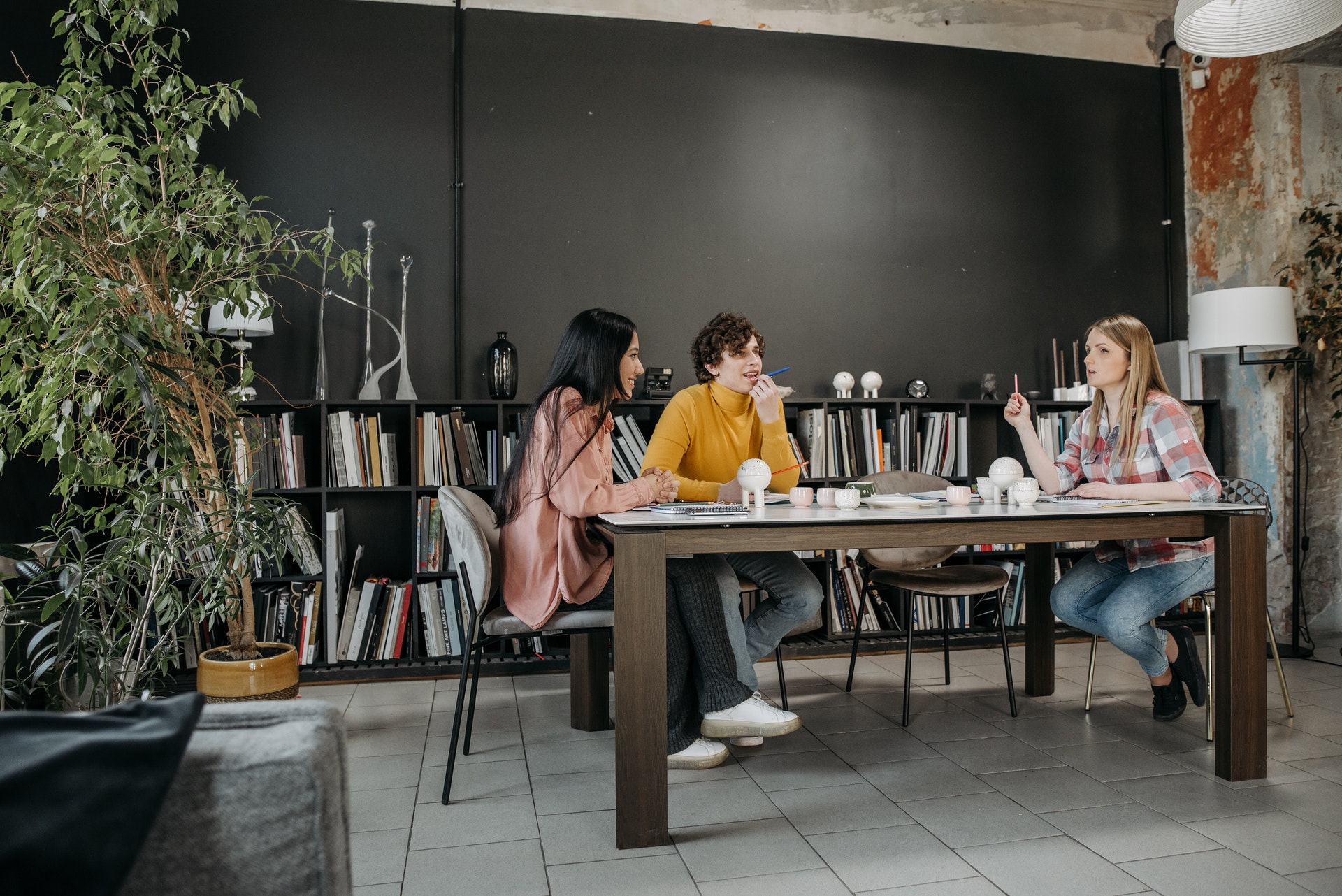 three-people-sitting-desk 3 colleagues in casual dress discuss HR operations