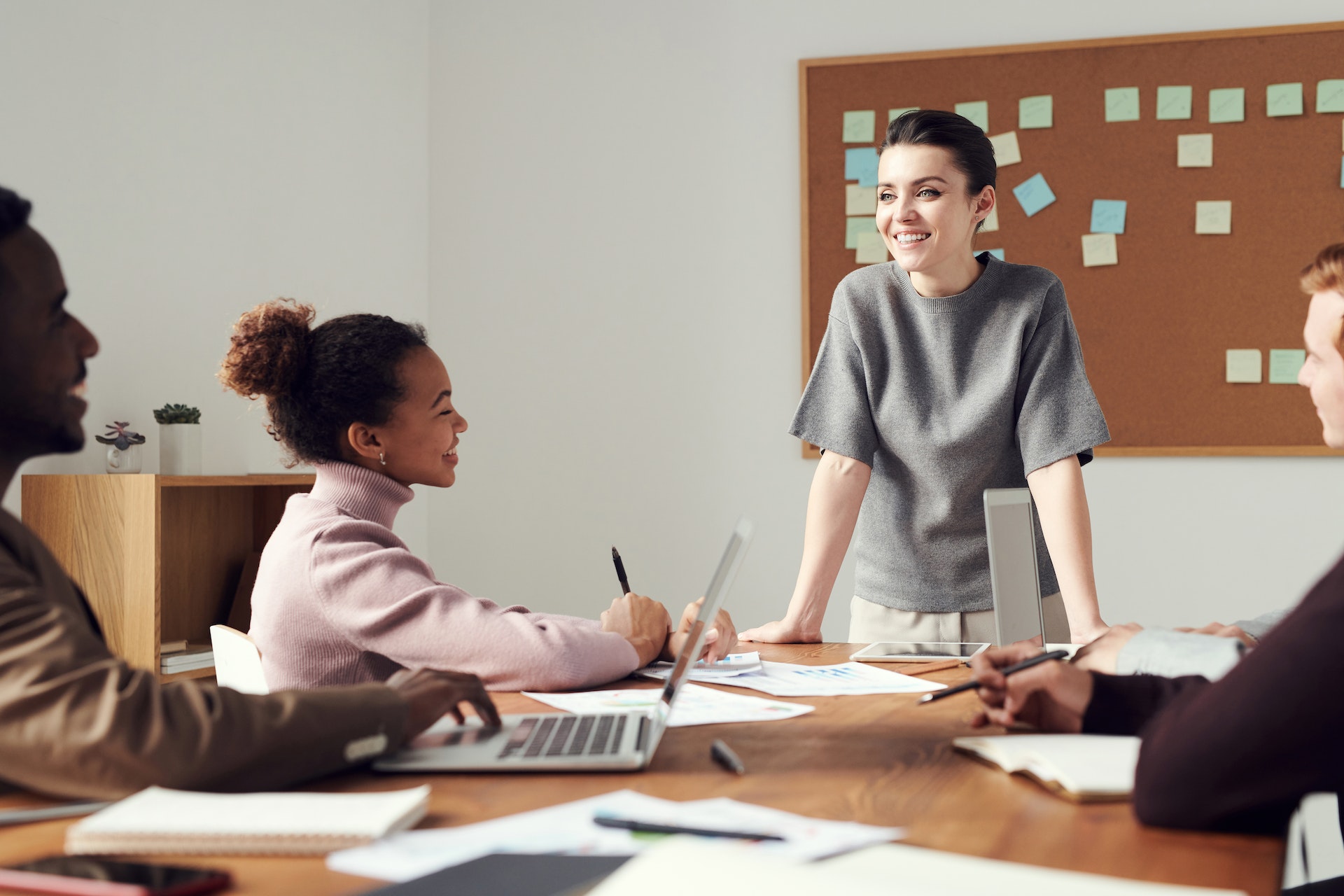 four-colleagues-meeting Woman with strong management values speaking to three seated colleagues