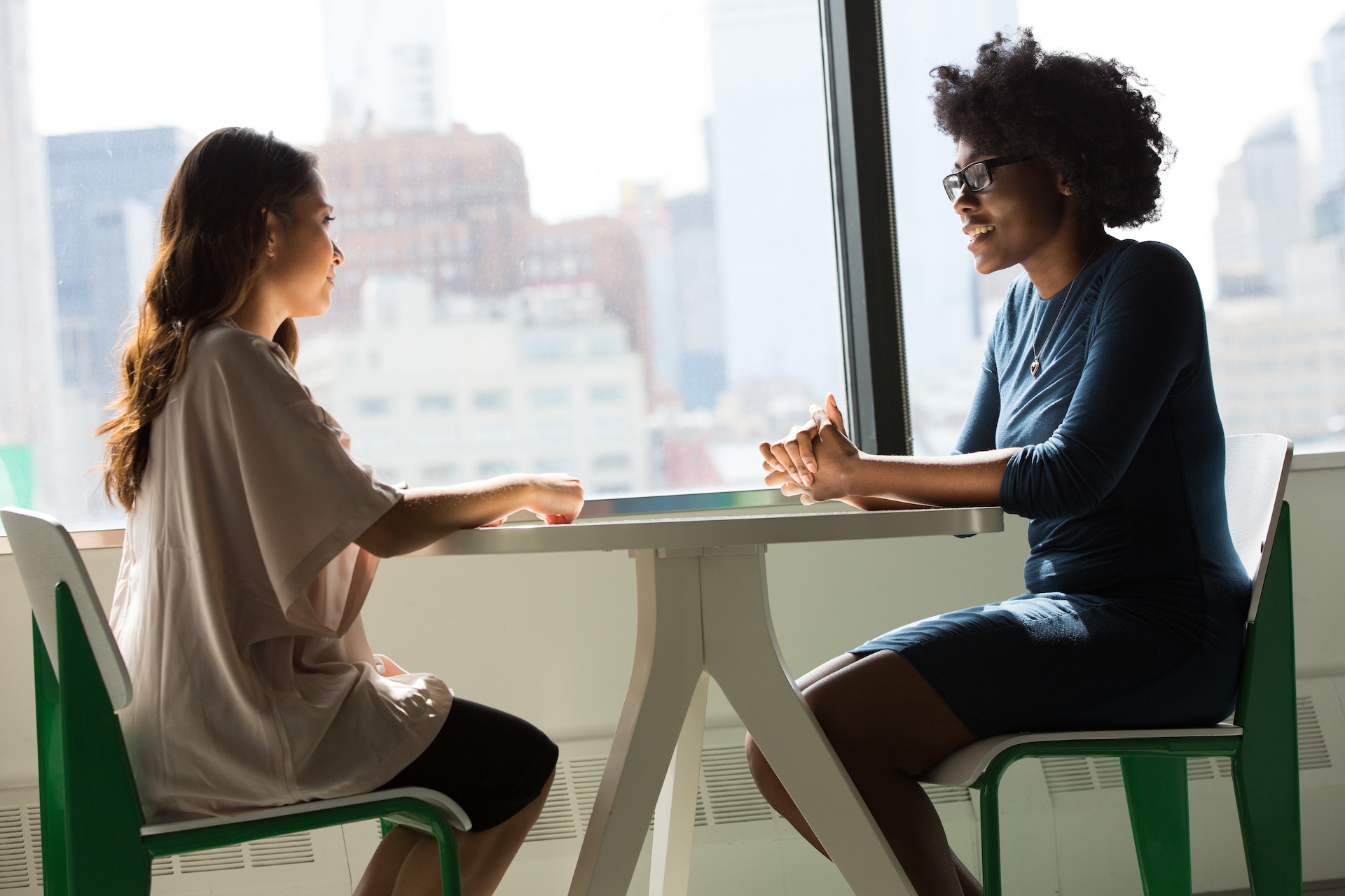 two-women-sitting-together Two women colleagues of different ethnicities discussing workforce diversity