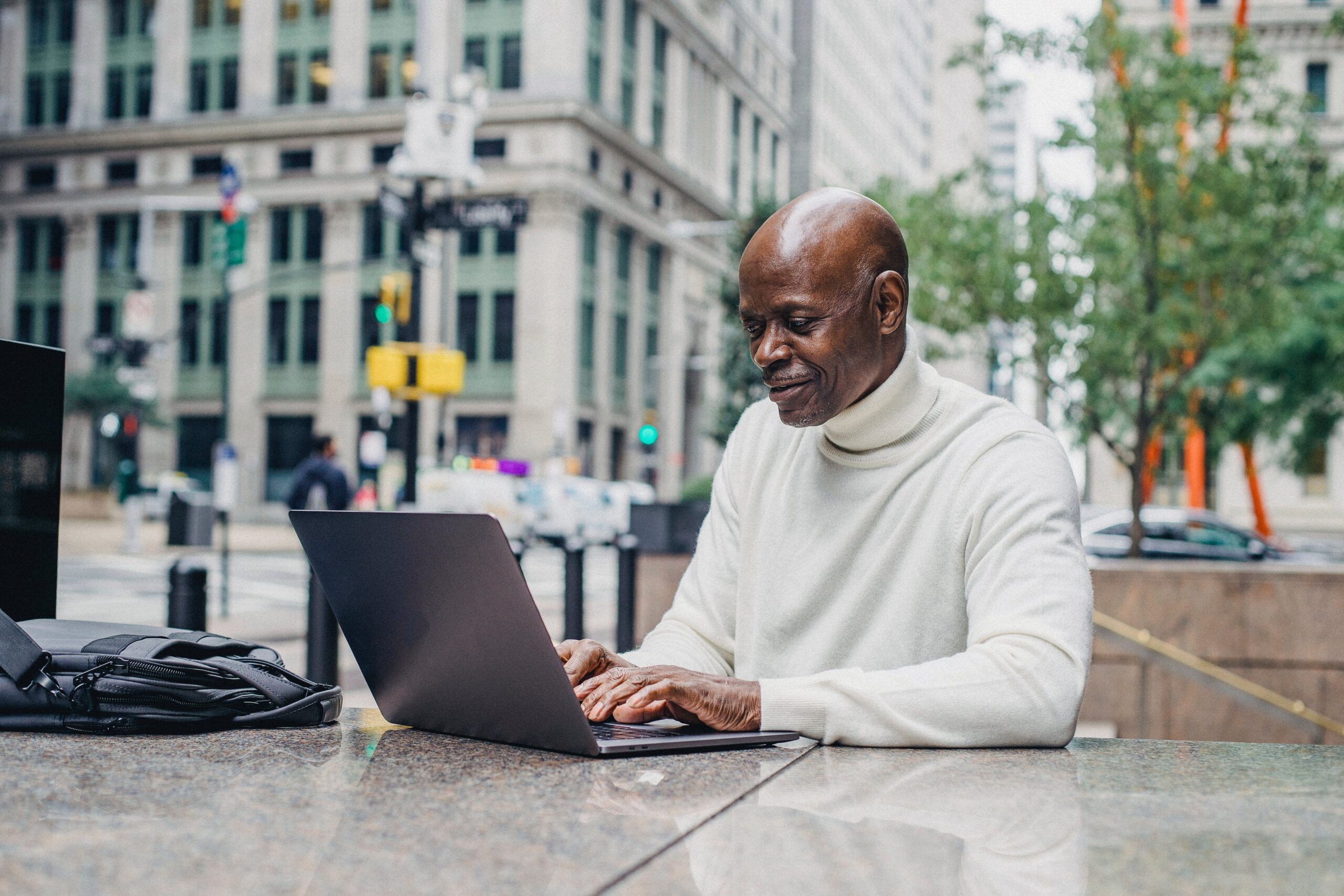 smiling-black-man-with-laptop-on-street An employee performing a self-review in a café outside